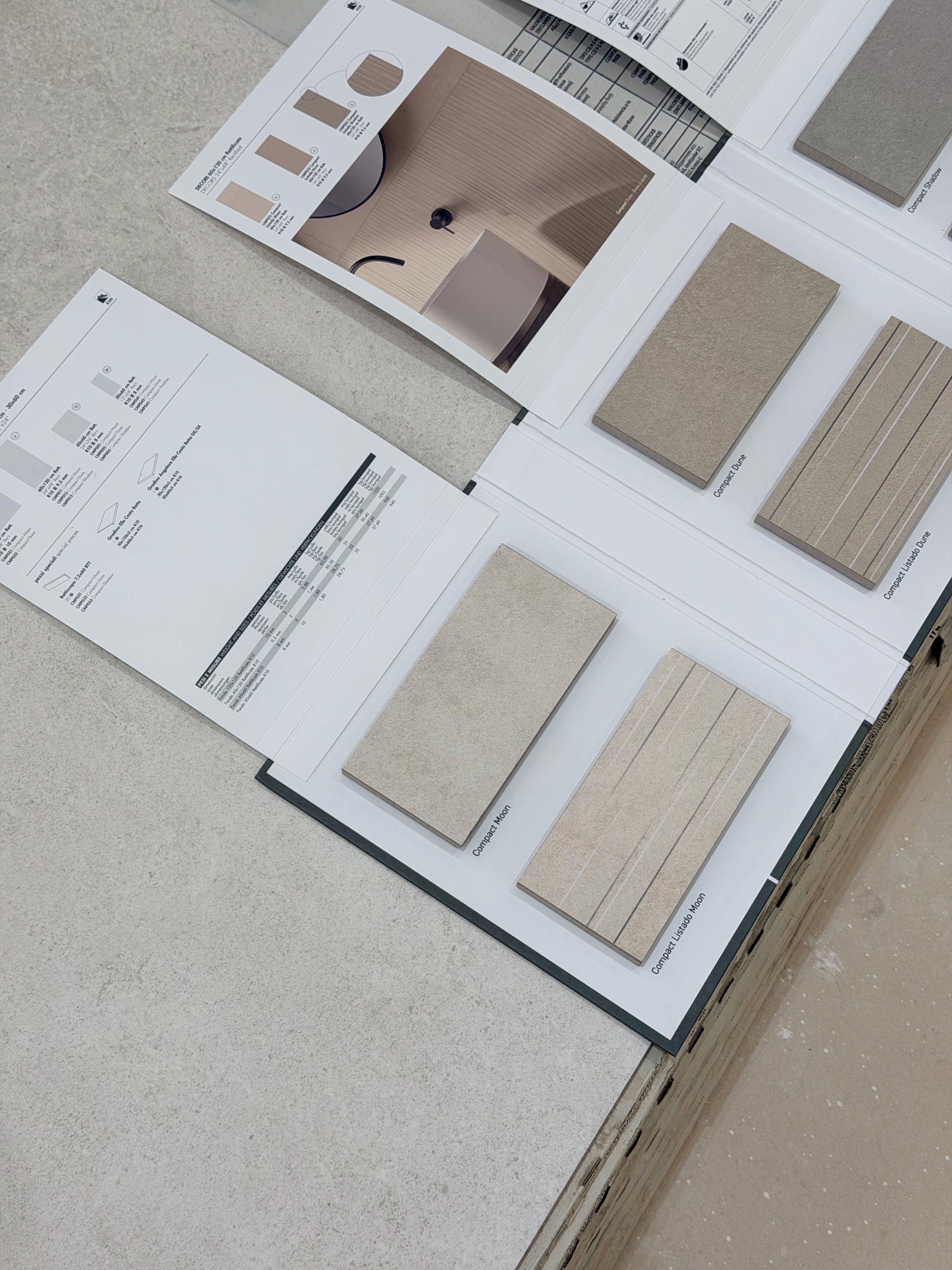 Tile sample boards with pale and darker neutral finishes compared in the house.
